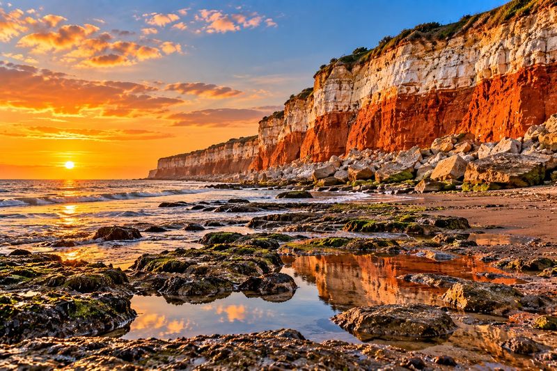 Hunstanton’s striped red and white cliffs glowing at sunset, with rock pools on the beach in front